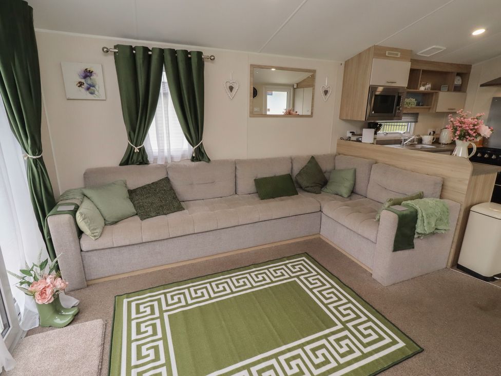 A living room with a sofa and kitchen unit at Homeslea 33 Millennium Gardens Morpeth