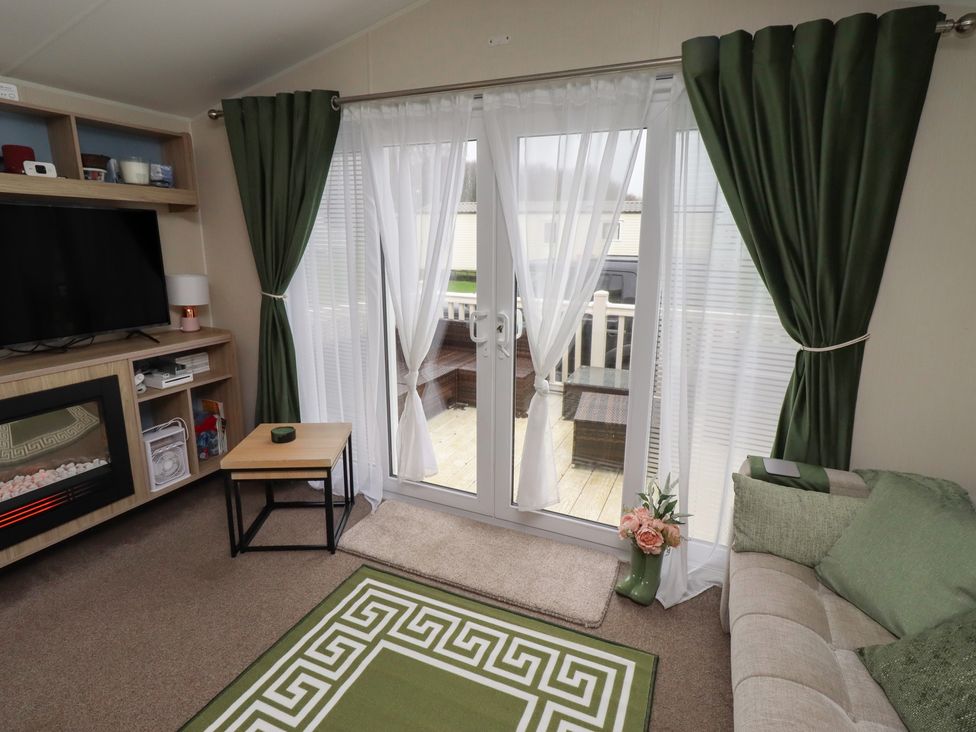 A living room with a television and sliding doors at Homeslea 33 Millennium Gardens in Morpeth