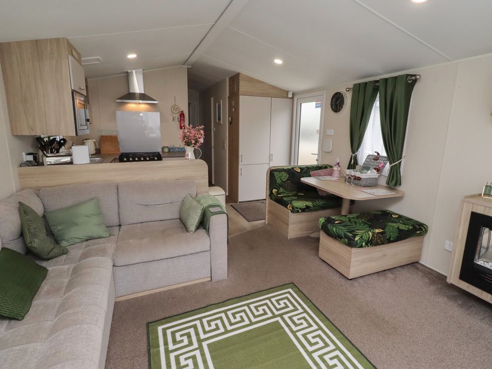 A living room with a sofa, dining table, and kitchen appliances at Homeslea 33 Millennium Gardens in Morpeth