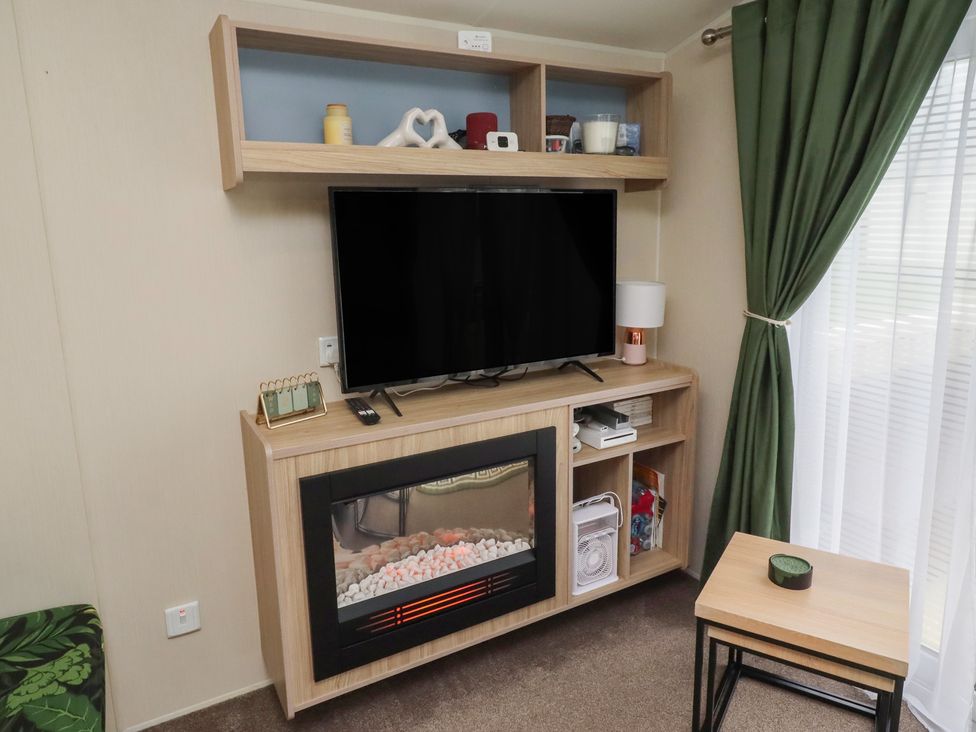 A living room with a television and a fireplace at Homeslea 33 Millennium Gardens Morpeth