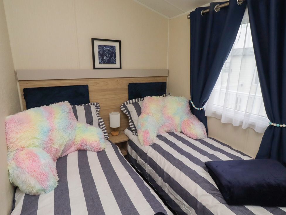 A bedroom with two beds, pillows, and a lamp at Homeslea 33 Millennium Gardens in Morpeth