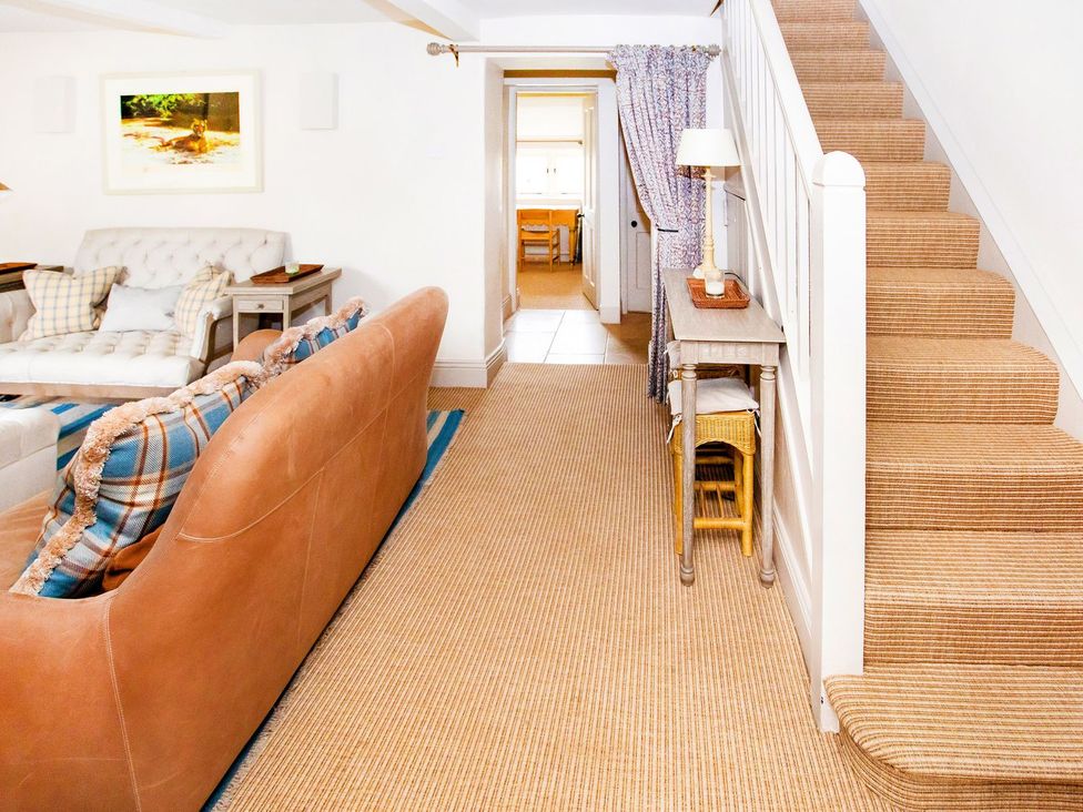 A living room with a sofa and staircase at Gardeners Cottage in Chipping Norton