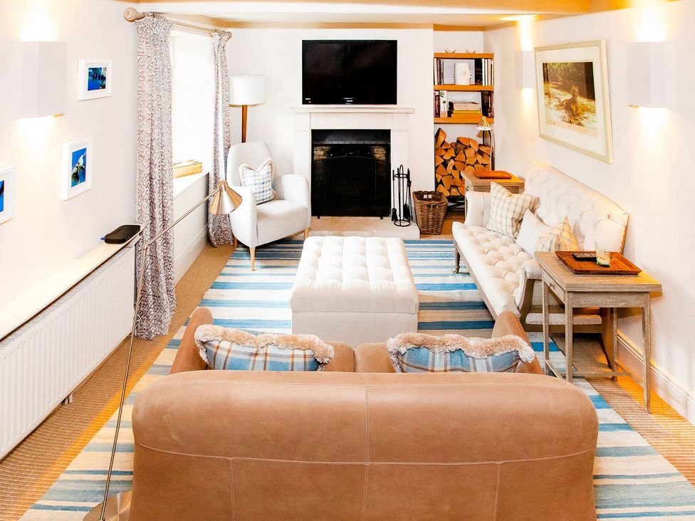 A living room with a sofa, coffee table, and television at Gardeners Cottage in Chipping Norton