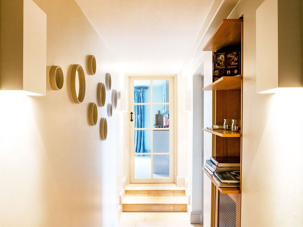 A hallway with shelves and a door at Gardeners Cottage in Chipping Norton