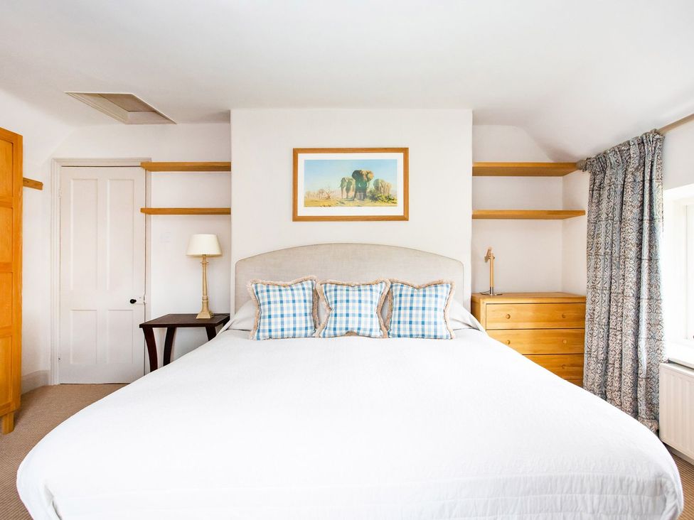 A bedroom with a bed, lamp, and dresser at Gardeners Cottage in Chipping Norton