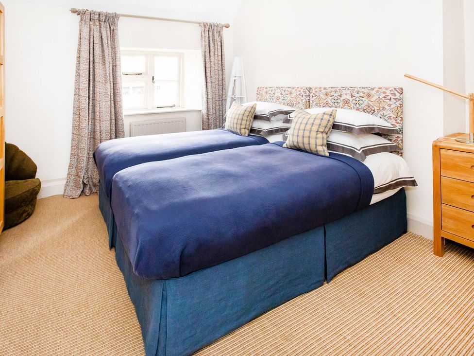 A bedroom with two beds and a bedside table at Gardeners Cottage in Chipping Norton