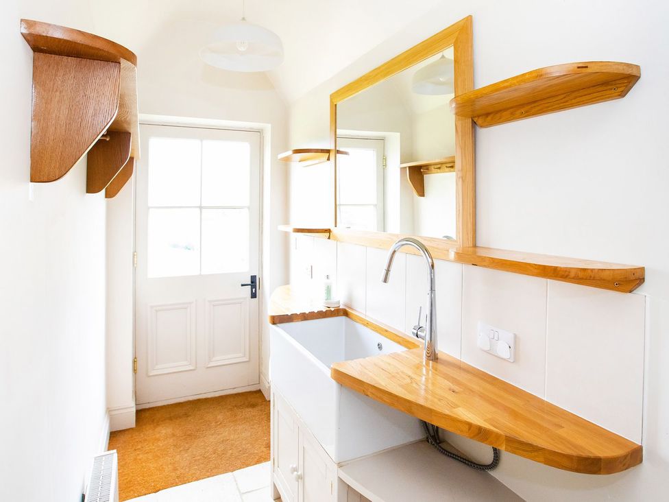 A bathroom with a sink and shelves at Gardeners Cottage in Chipping Norton