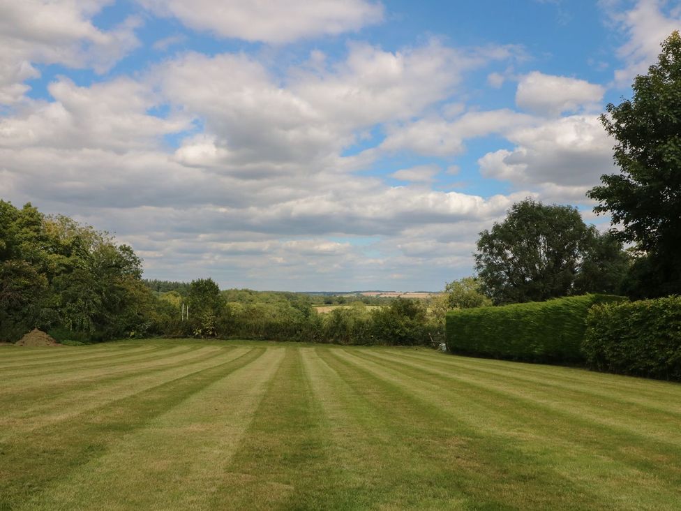 A garden with a lawn and trees at Gardeners Cottage in Chipping Norton