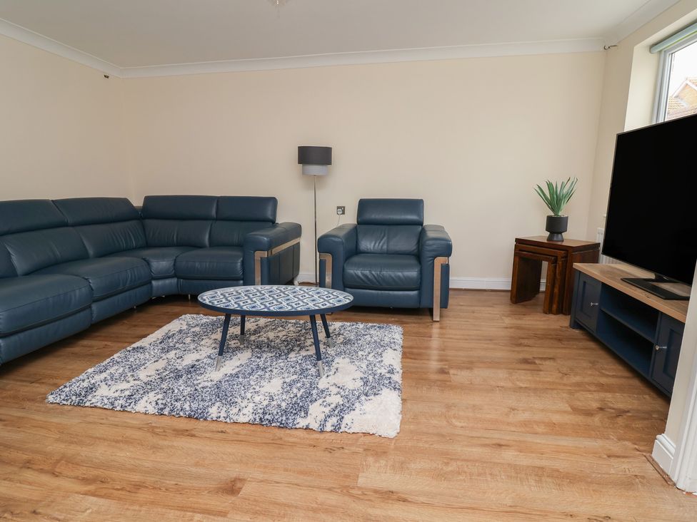 A living room with a sofa, armchair and coffee table at 31 Llys Ogwen in Prestatyn