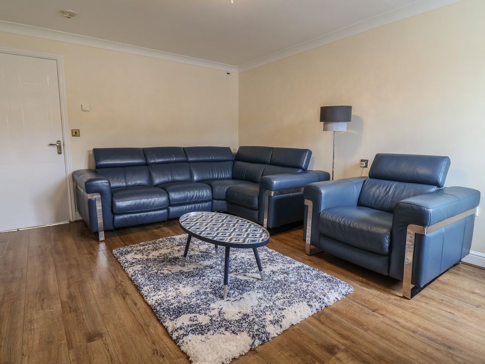 A living room with a sofa, armchair, coffee table, and lamp at 31 Llys Ogwen Prestatyn