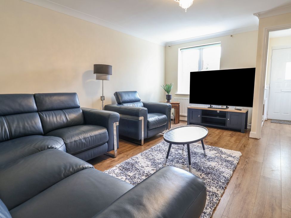 A living room with sofa, coffee table, and television at 31 Llys Ogwen in Prestatyn