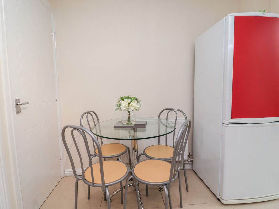 A dining room with a glass table and four chairs at 31 Llys Ogwen Prestatyn