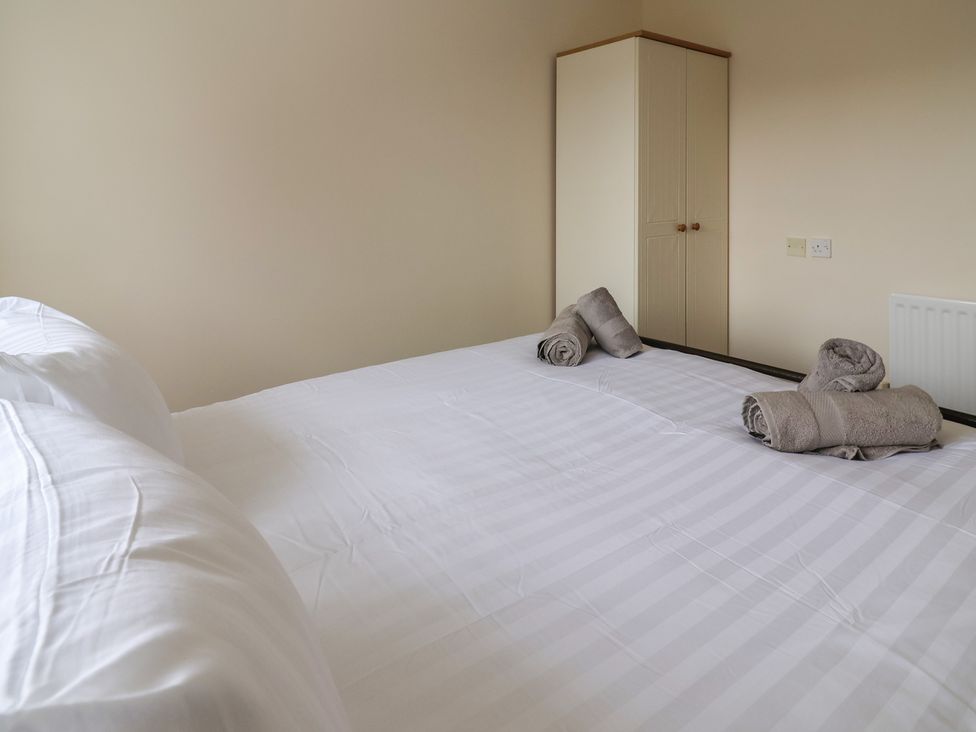 A bedroom with a bed and towels on the covers at 31 Llys Ogwen, Prestatyn