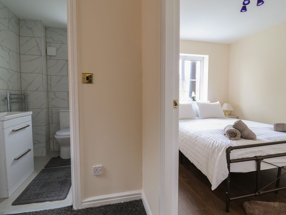 A bathroom with toilet and wash basin leading to a bedroom with a bed at 31 Llys Ogwen Prestatyn