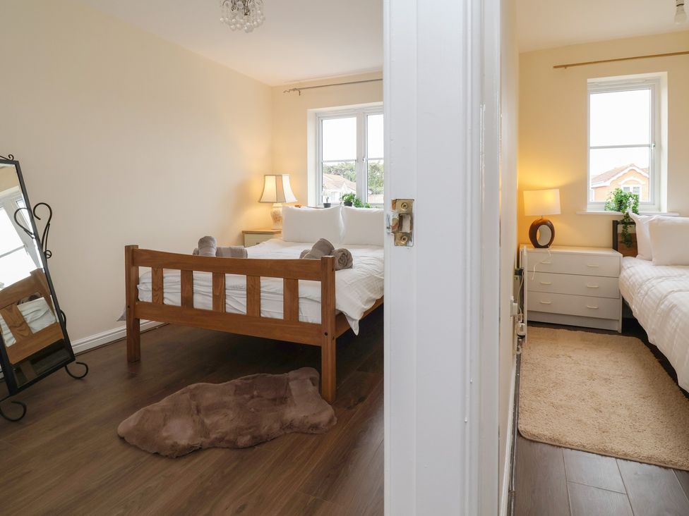 A bedroom with two beds, a dresser, and a mirror at 31 Llys Ogwen in Prestatyn