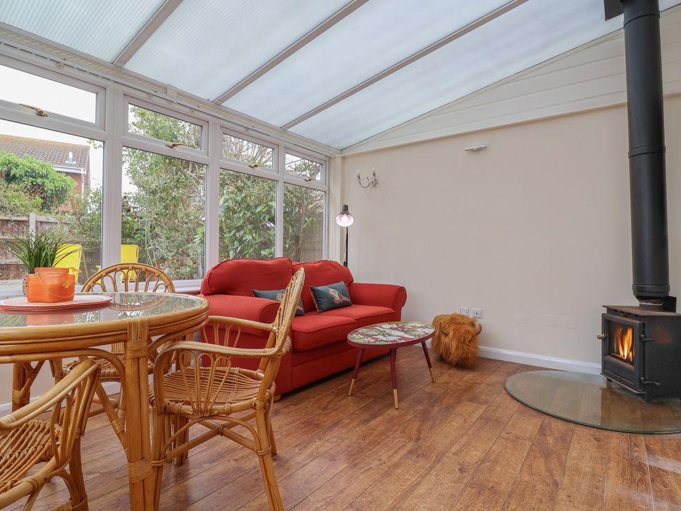 A conservatory with a red sofa and table at 31 Llys Ogwen in Prestatyn
