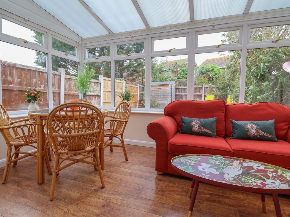 A conservatory with rattan furniture and a coffee table at 31 Llys Ogwen in Prestatyn