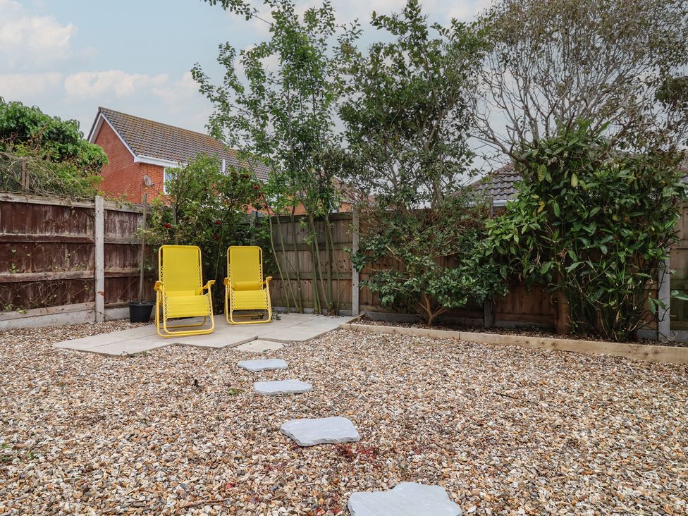A garden with yellow chairs and stepping stones at 31 Llys Ogwen Prestatyn