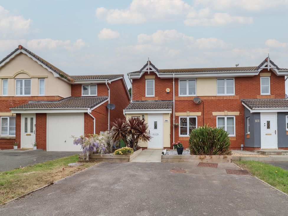 A house with a garage and plants in the garden at 31 Llys Ogwen Prestatyn