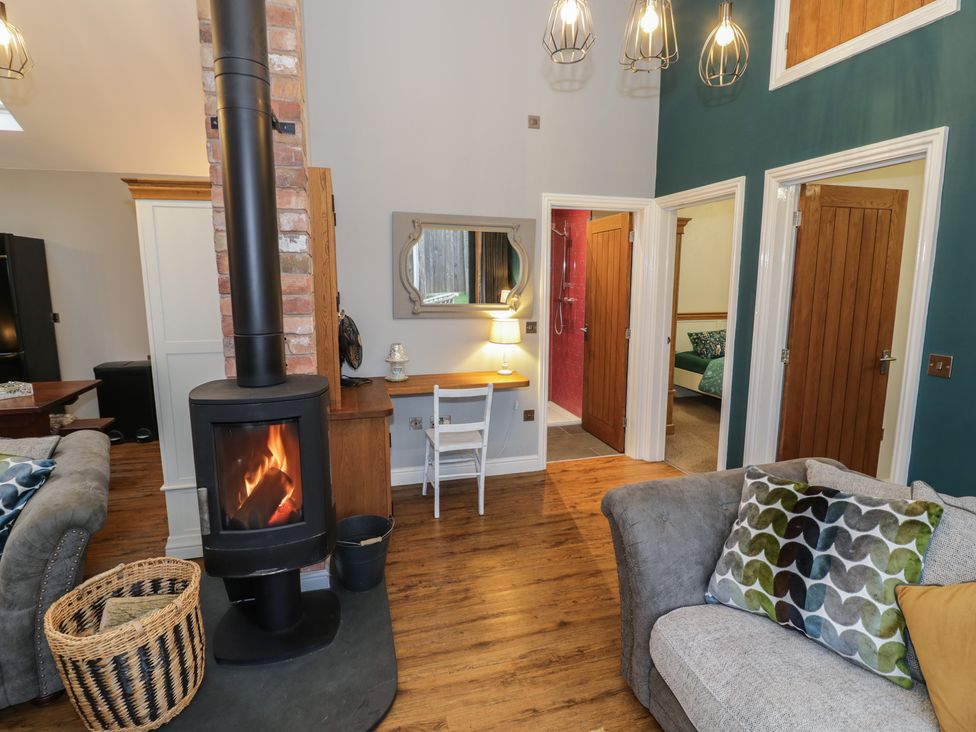 A living room with a wood stove and a sofa at Otter's Rest in Droitwich