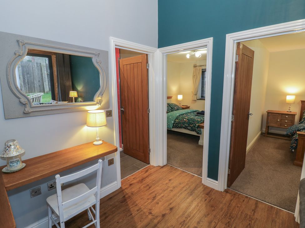 A hallway with a mirror, desk, and doors leading to bedrooms at Otter's Rest in Droitwich
