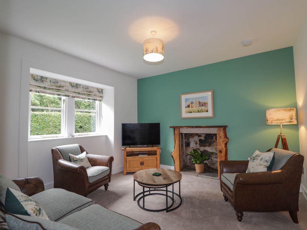 A living room with a sofa, armchairs, and a TV at Station Lodge near Forres