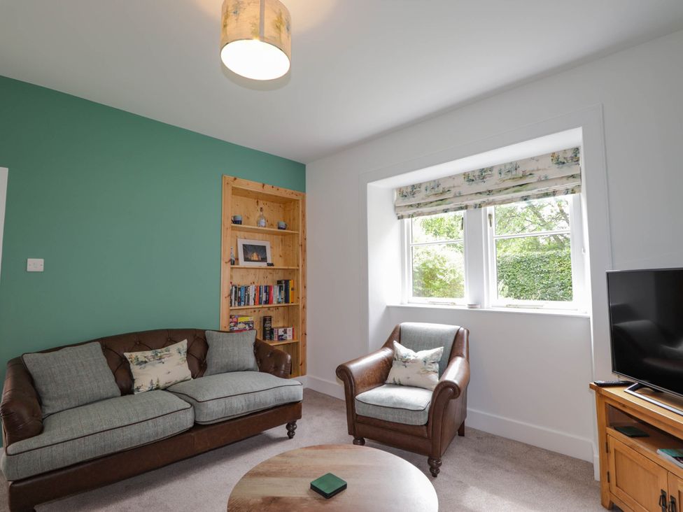 A living room with a sofa and bookshelf at Station Lodge near Forres