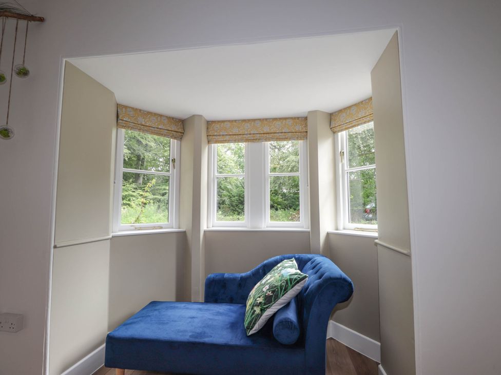 A snug with a blue couch and windows at Station Lodge near Forres