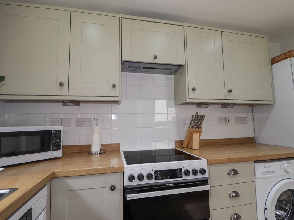 A kitchen with cabinets, cooker, and microwave at Station Lodge near Forres
