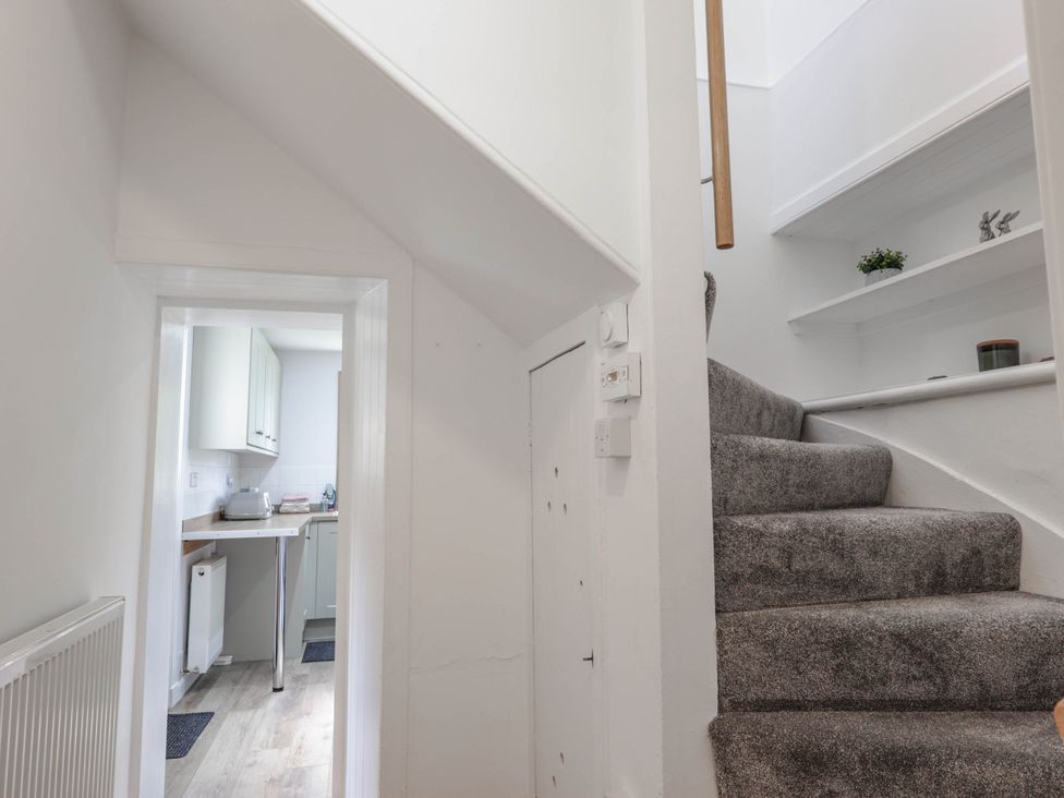 A hallway with a staircase and a view into the kitchen at Station Lodge near Forres