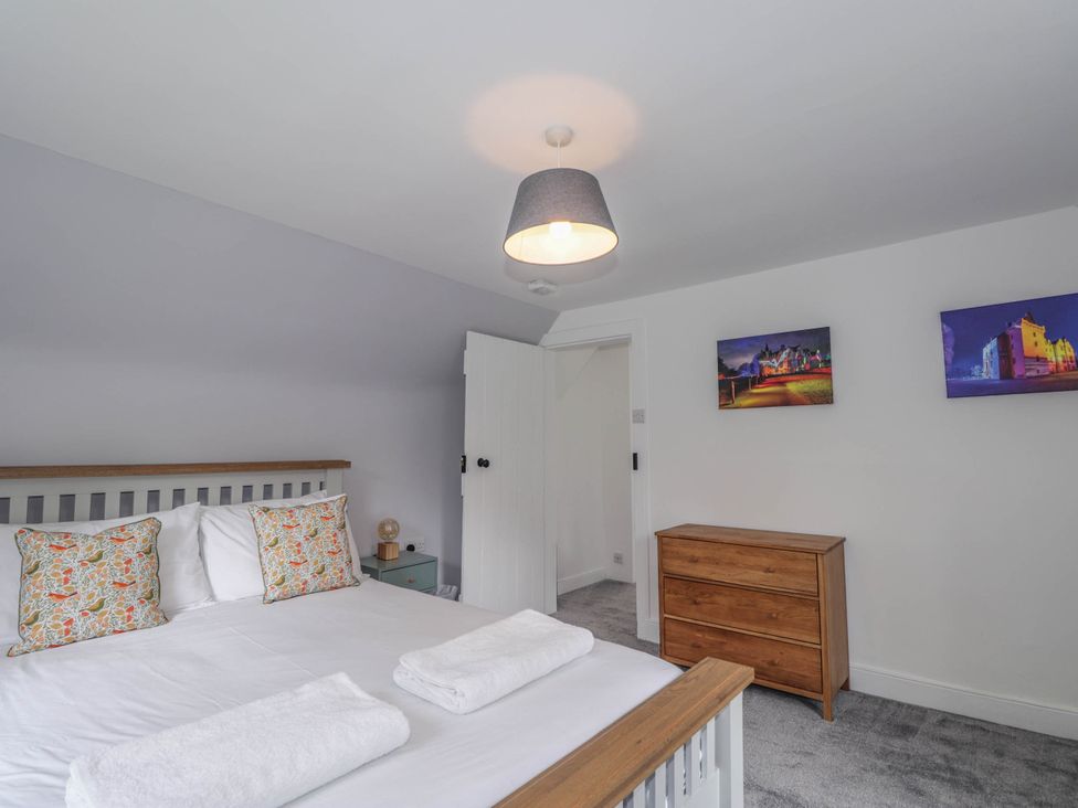 A bedroom with a bed, dresser and wall art at Station Lodge near Forres