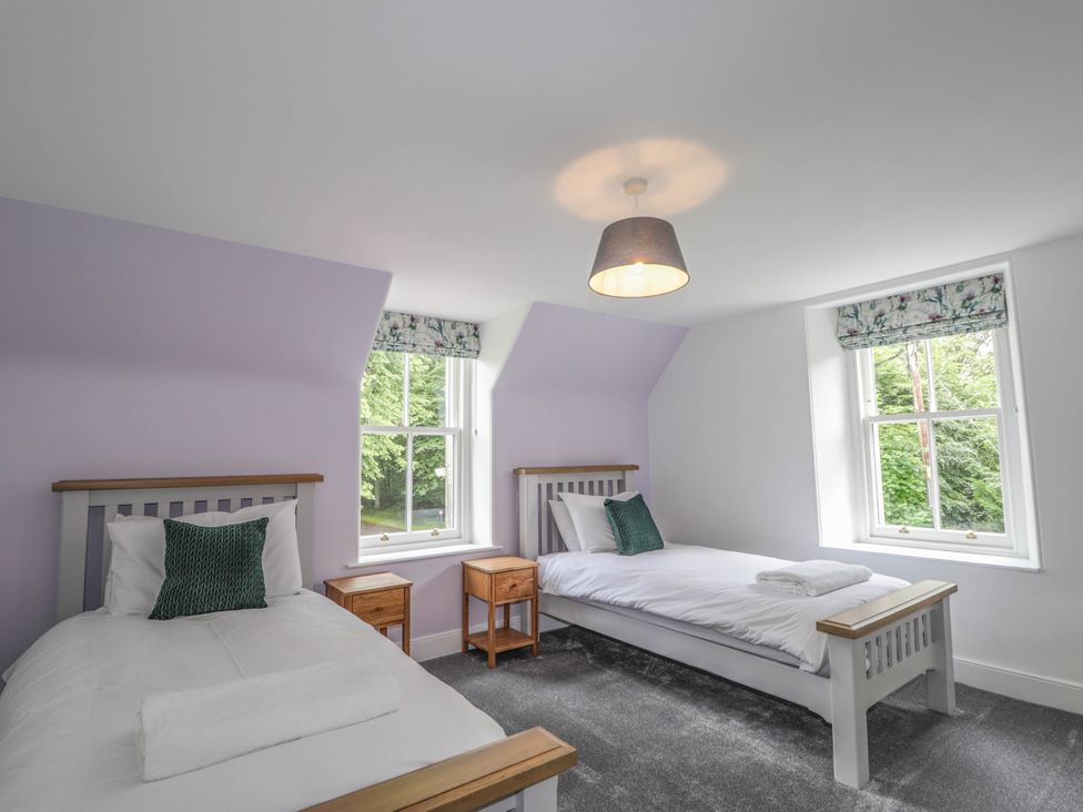 A bedroom with two beds and windows at Station Lodge near Forres