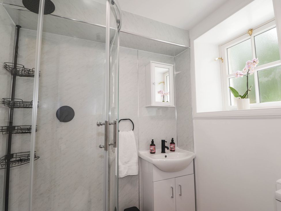A bathroom with a shower, sink, and window at Station Lodge near Forres