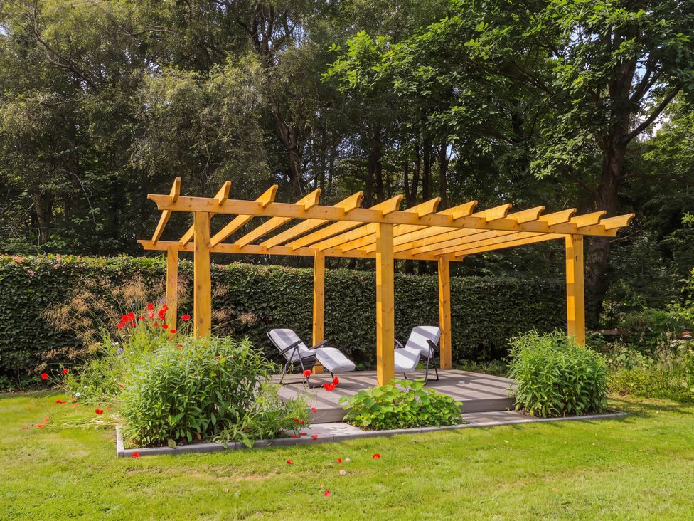 A garden with a pergola and chairs at Station Lodge near Forres