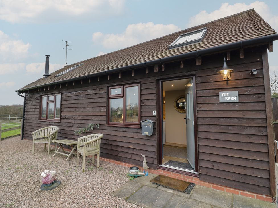 An exterior view of a barn with chairs and a table at The Barn on The Lagoon Droitwich