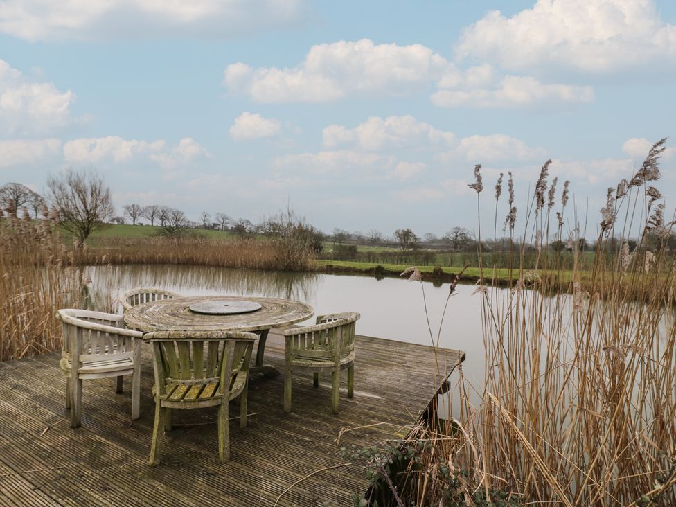 An outdoor space with a table and chairs by the water at The Barn on The Lagoon in Droitwich