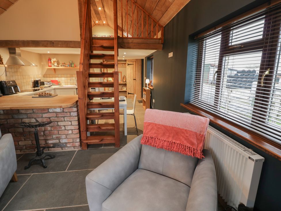 A living room with a staircase and sofa at The Barn on The Lagoon in Droitwich