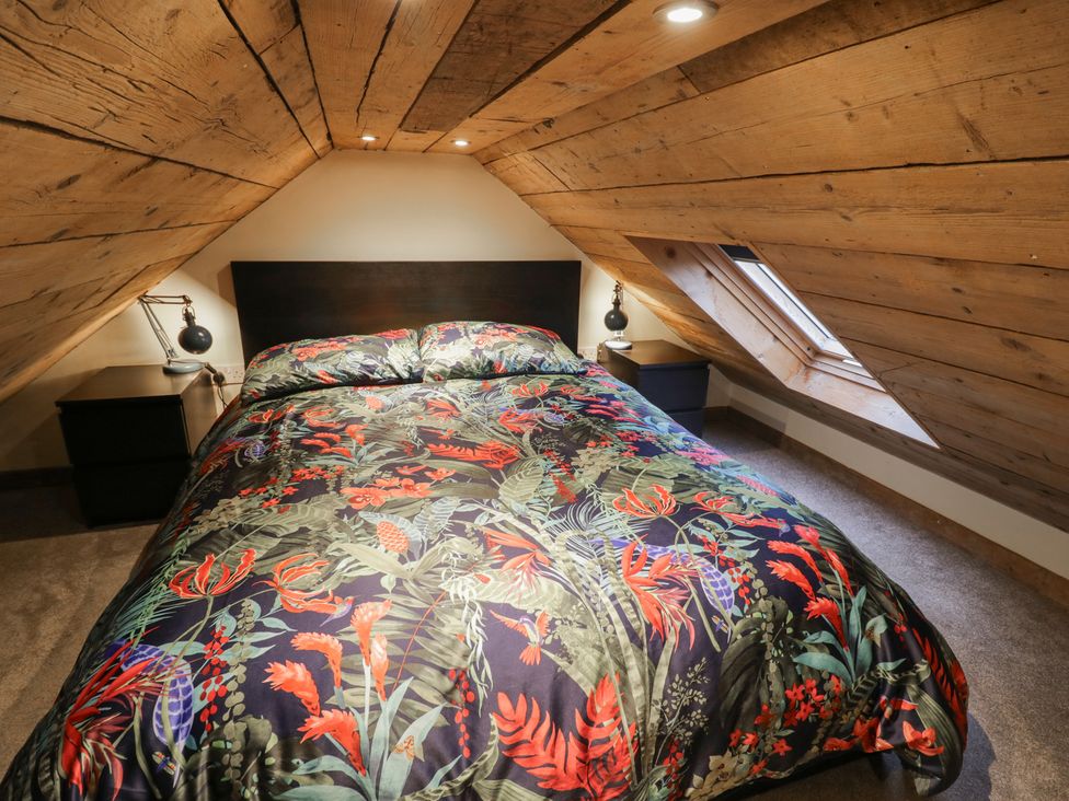 A bedroom with a bed and nightstand at The Barn on The Lagoon Droitwich
