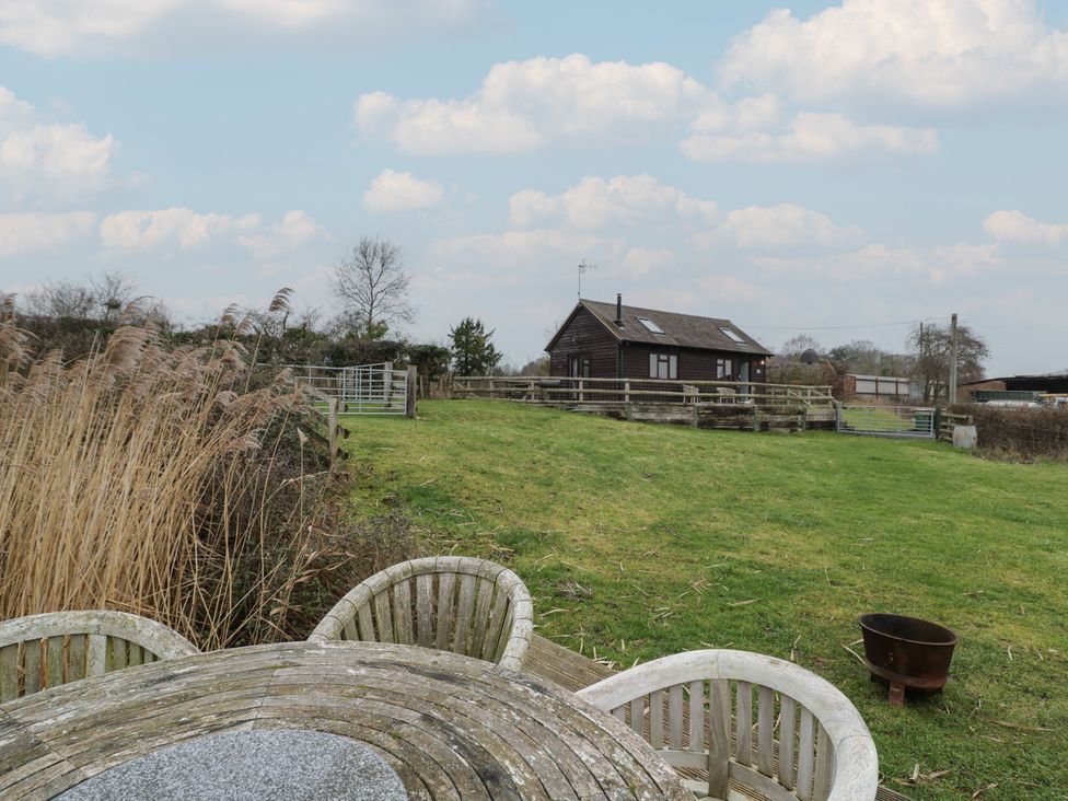 An outdoor area with a table and chairs near a house at The Barn on The Lagoon Droitwich