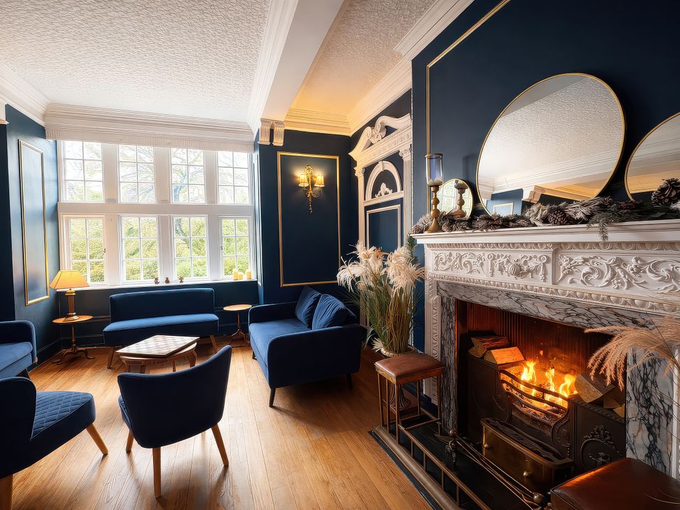A living room with a fireplace and seating area at Hanlith Hall near Malham