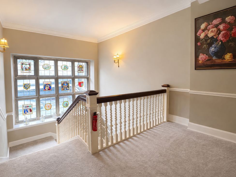 A staircase with a stained glass window and paintings at Hanlith Hall near Malham