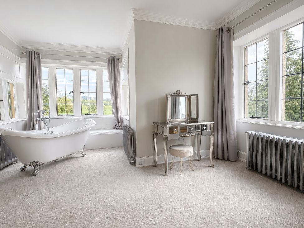 A bathroom with a bathtub and dressing table at Hanlith Hall near Malham