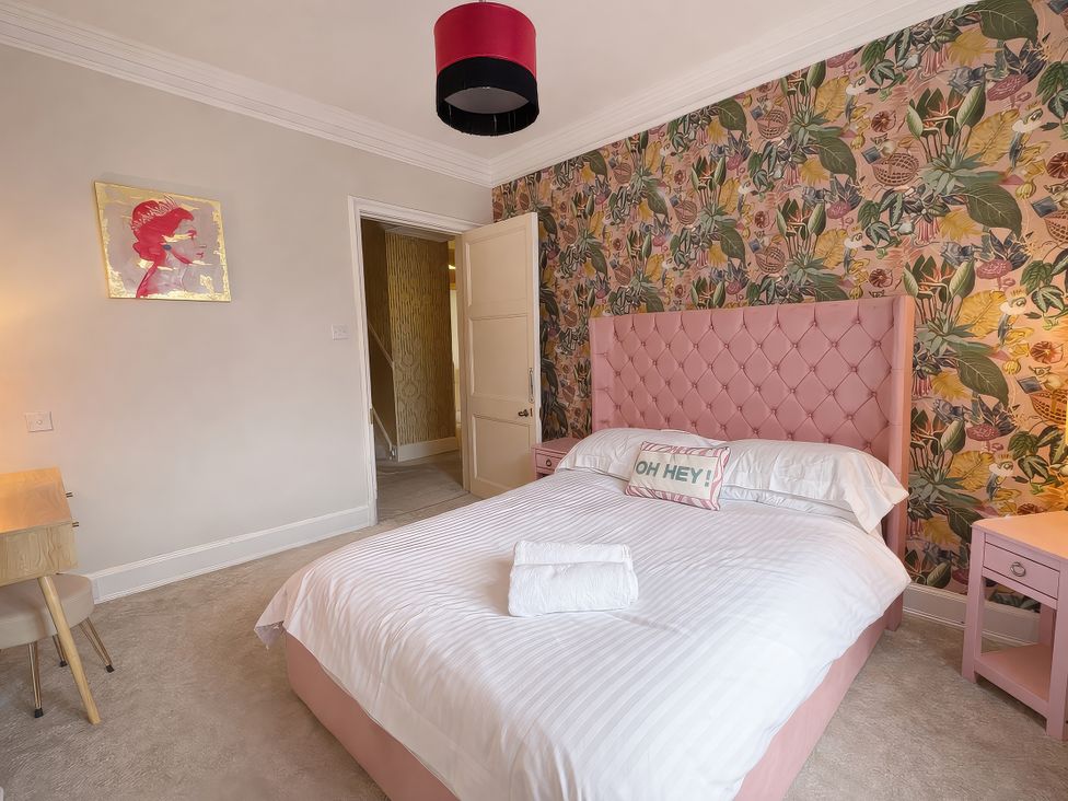 A bedroom with a pink bed and artwork on the wall at Hanlith Hall in Hanlith near Malham