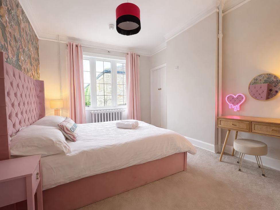 A bedroom with a pink bed and neon sign at Hanlith Hall in Hanlith near Malham