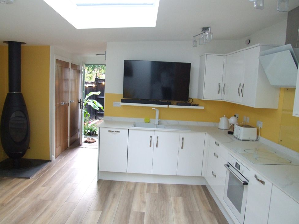 A kitchen with a television and appliances at Woodland Lodge The Snug Filby