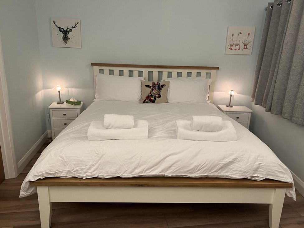 A bedroom with a bed and nightstands at Woodland Lodge The Snug in Filby
