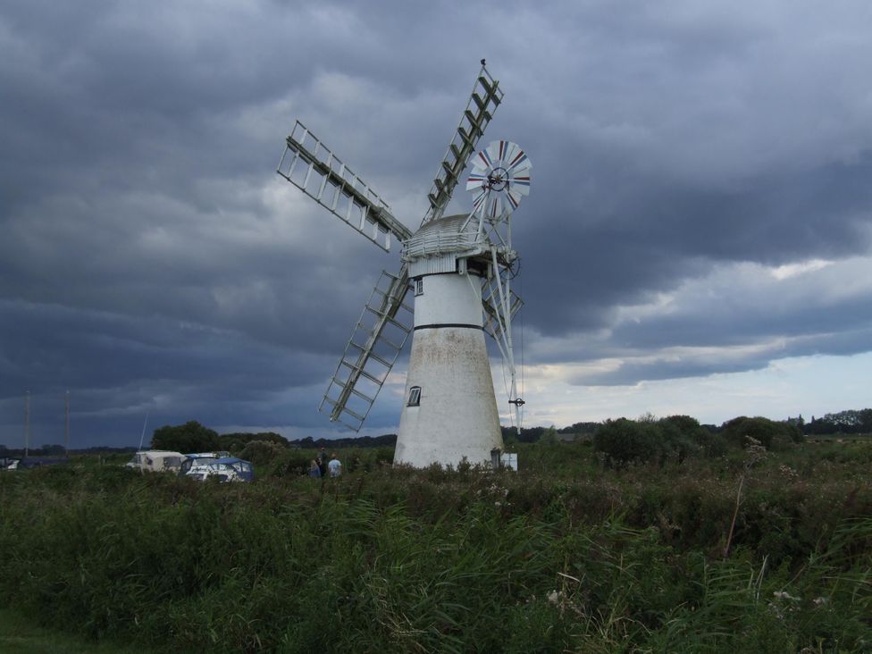 A windmill with clouds in the sky at Woodland Lodge The Snug, Filby