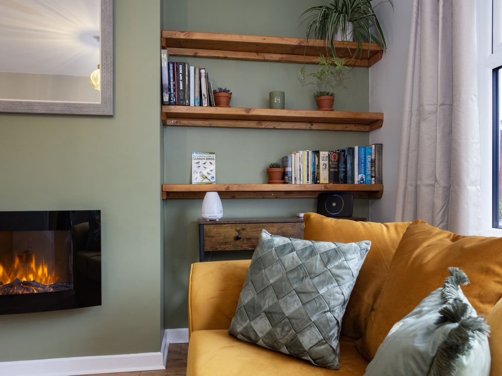 A living room with a shelf of books and a sofa at Thieveley Pike View in Burnley