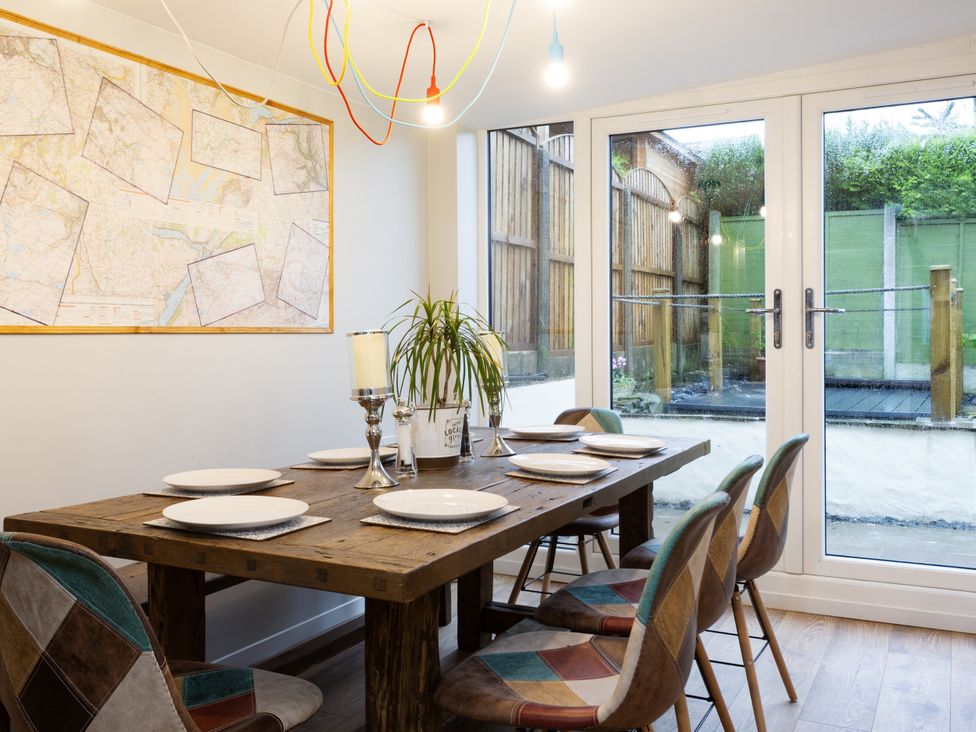 A dining room with a wooden table and six chairs at Thieveley Pike View in Burnley