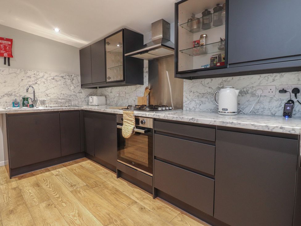 A kitchen with dark cabinets and marble countertops at Thieveley Pike View in Burnley